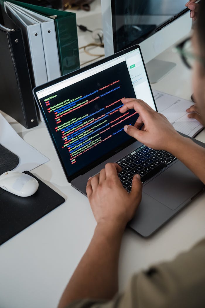 about-01 Close-up of a programmer pointing at a colorful code script on a laptop in an office setting.